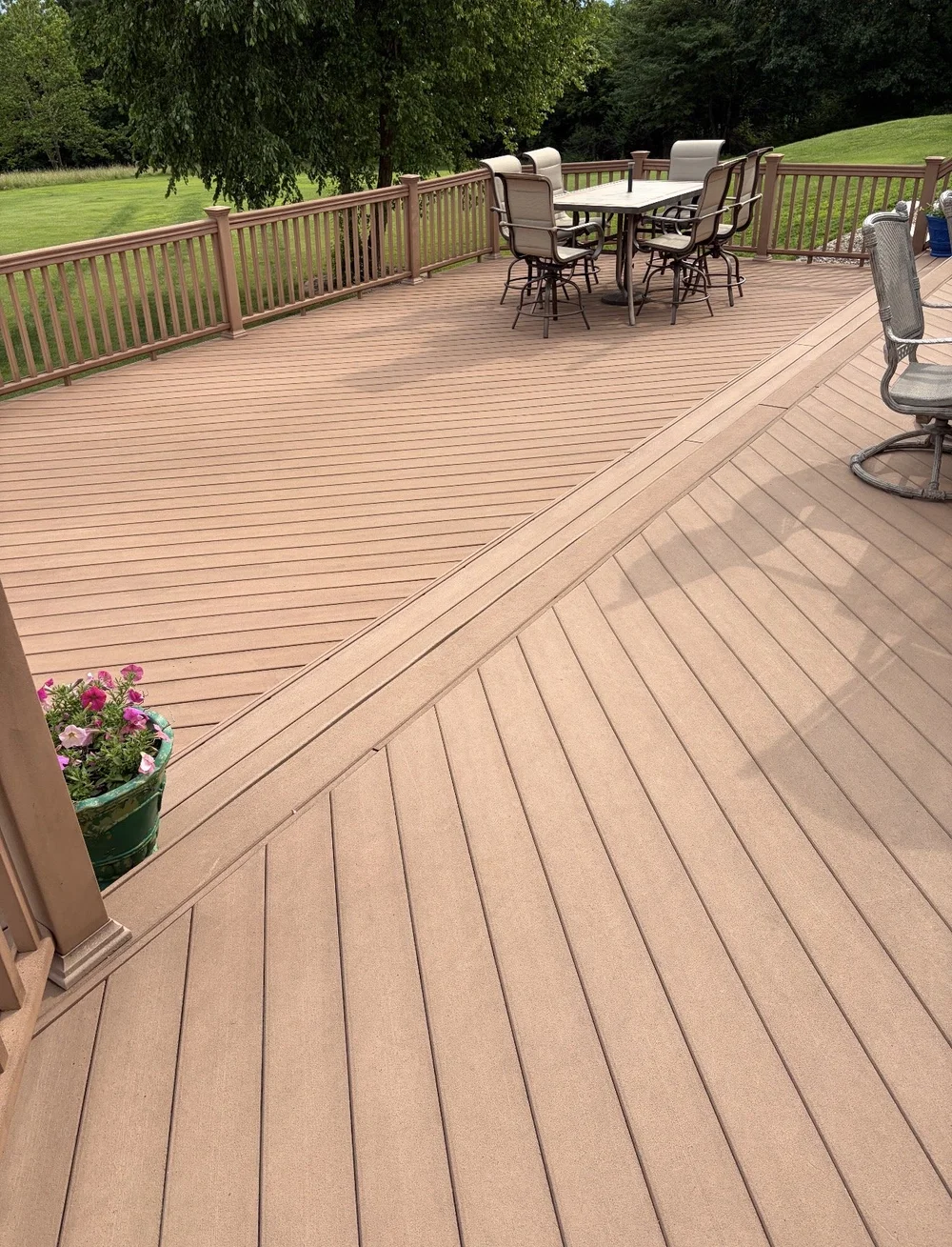 A large restored backyard composite deck with patio furniture, clean and even after professional cleaning.