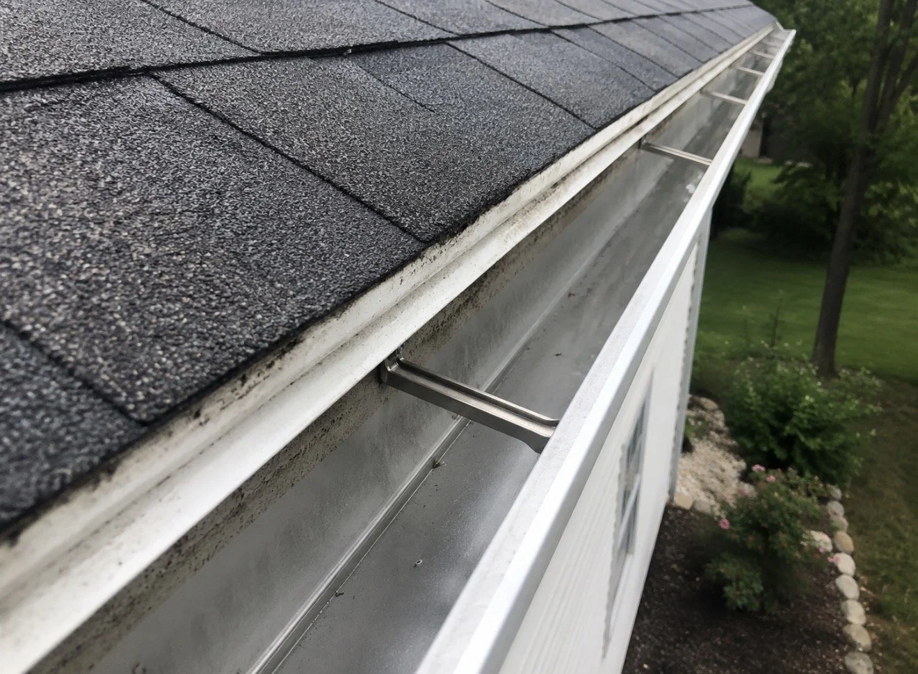 A clean white rain gutter running along the edge of a shingled roof.